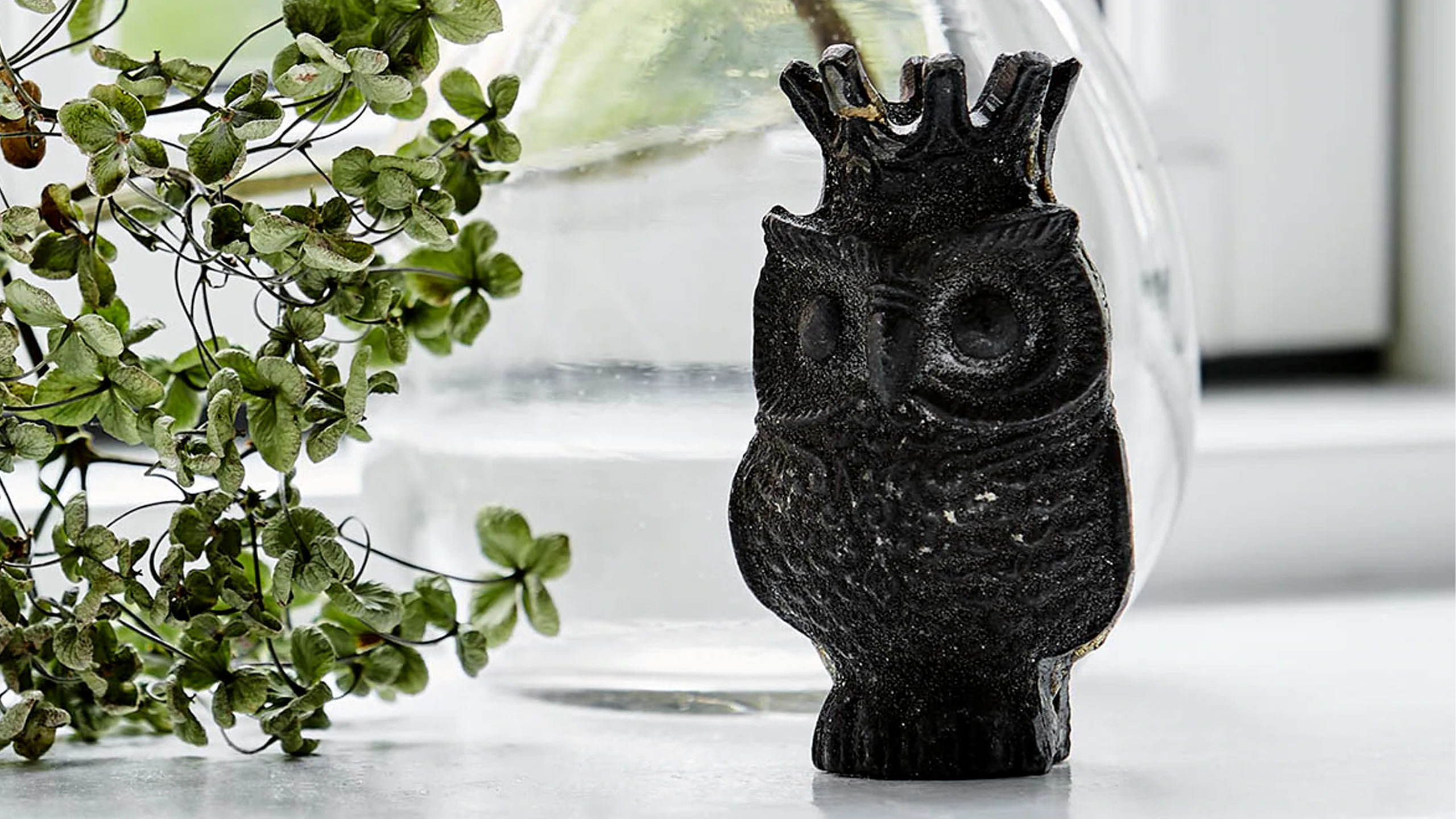 schwarze sika design glücksbringer figur eule neben einer pflanze