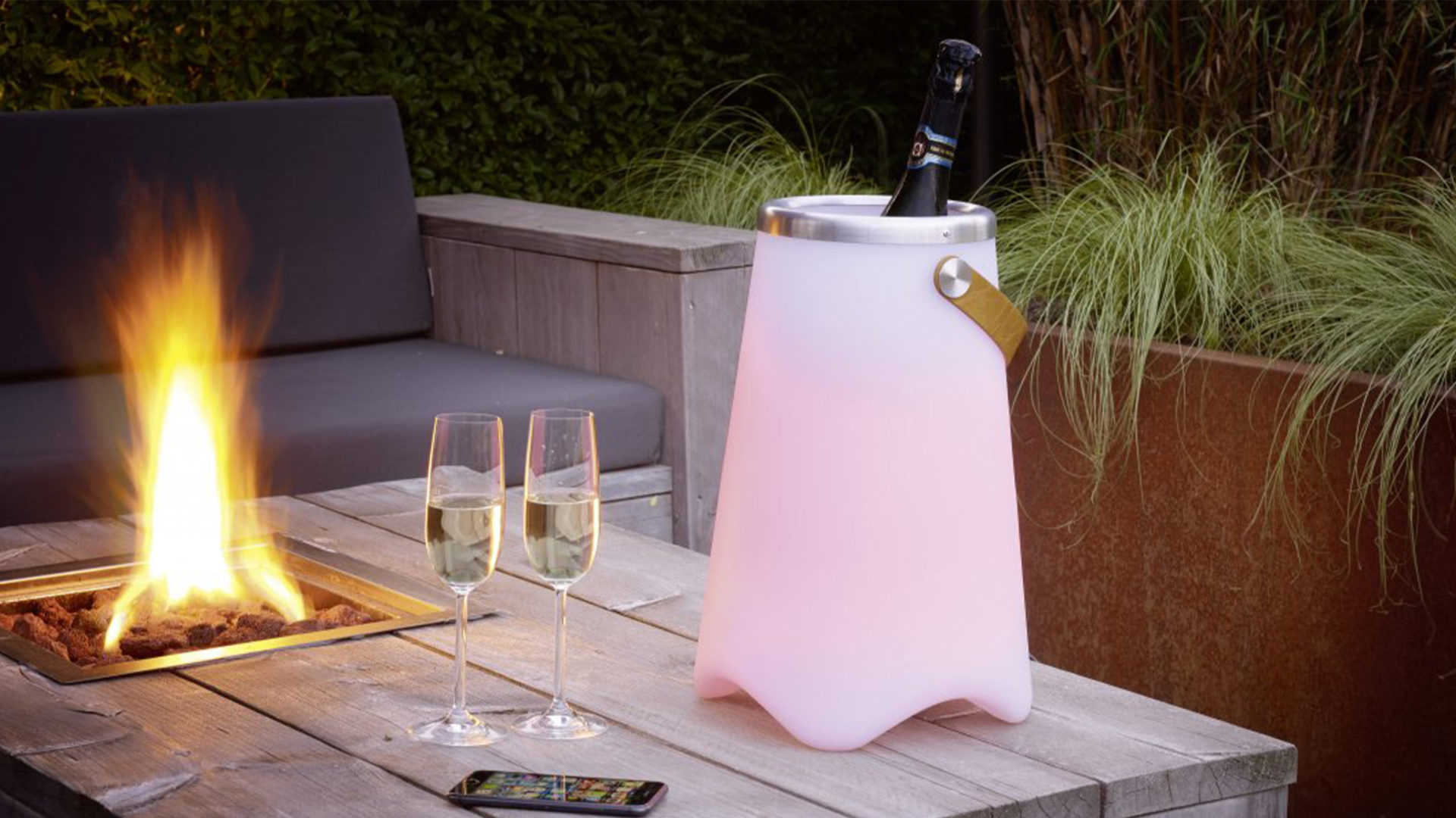 trio leuchten jamaica getränkekühler mit sektflasche und led licht in pink neben einem feuer auf der terrasse am tisch