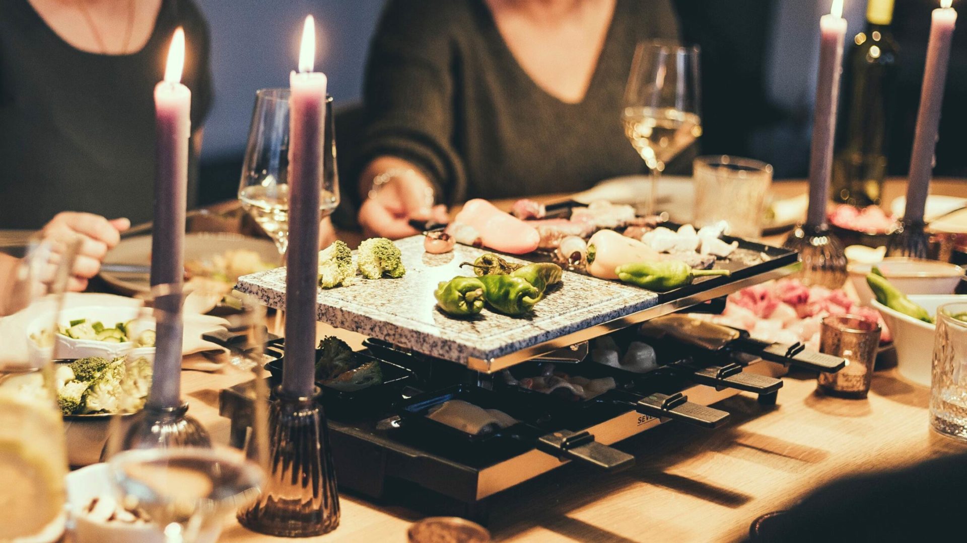 raclette essen auf einem festtagstisch mit kerzen