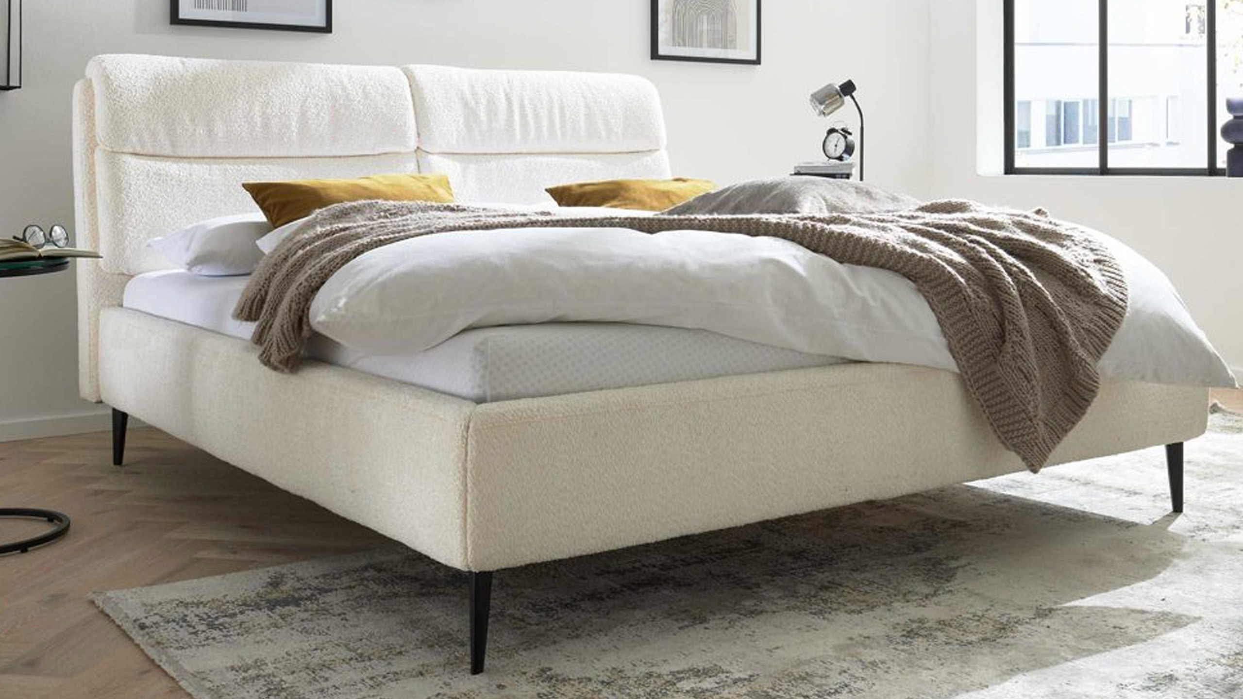 interliving 1416 polsterbett aus chenille in weiß mit gelben kissen und einer braunen decke
