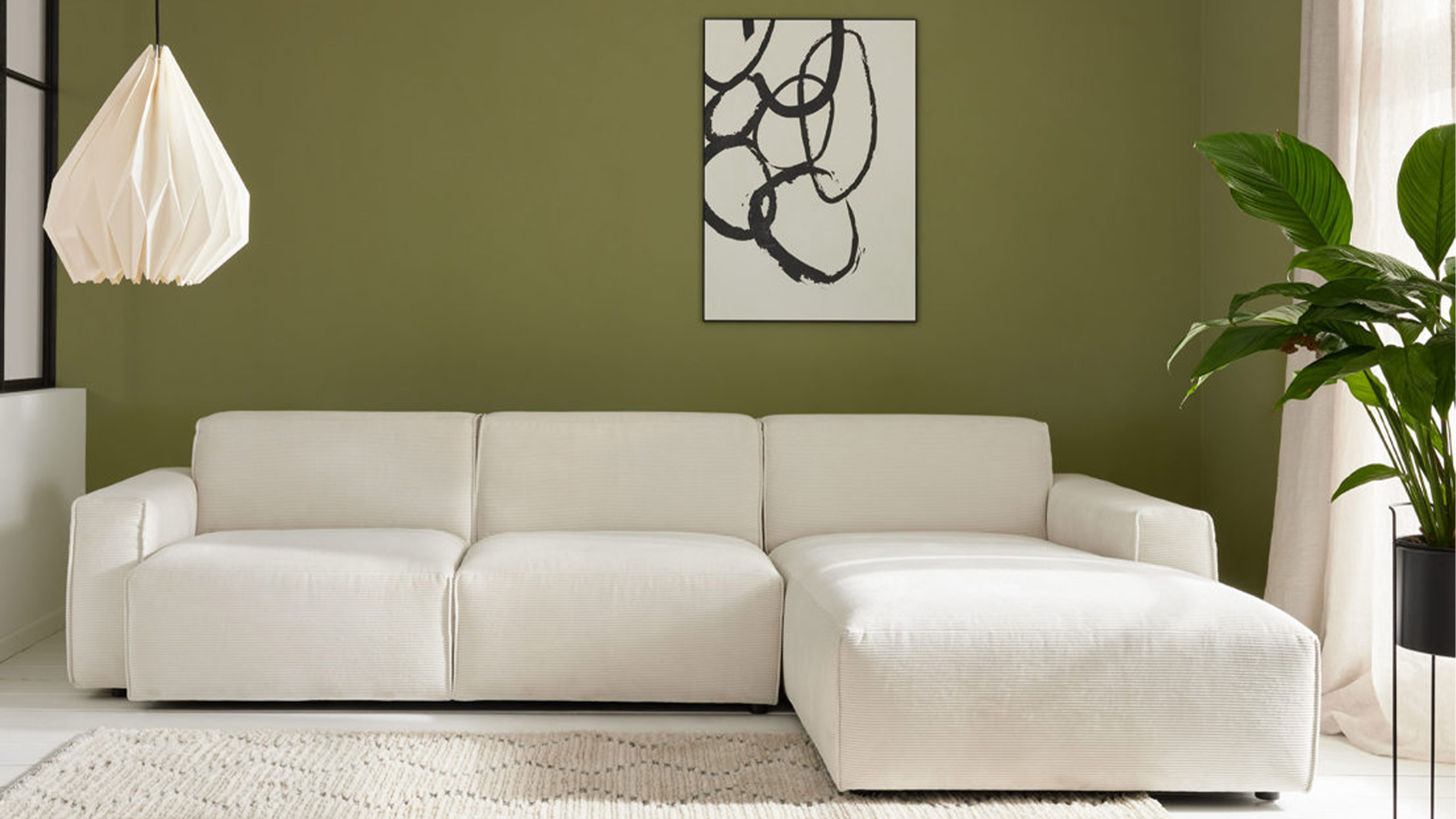 roomio no 4100 sofa in creme vor einer grünen wand