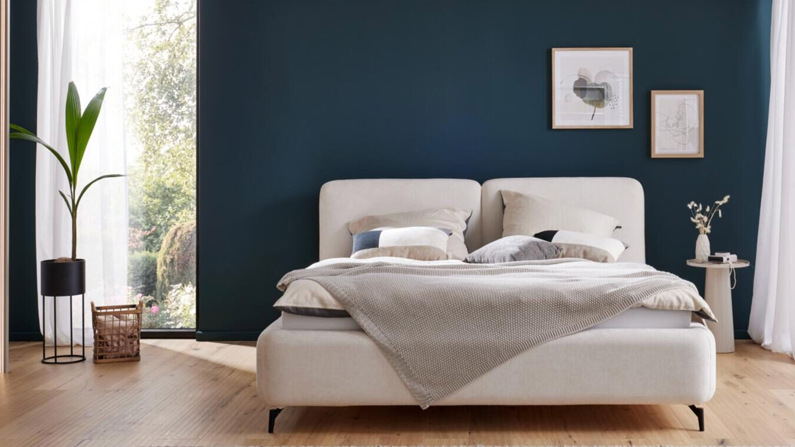 weißes interliving 1419 polsterbett vor einer dunkelblauen wand im schlafzimmer