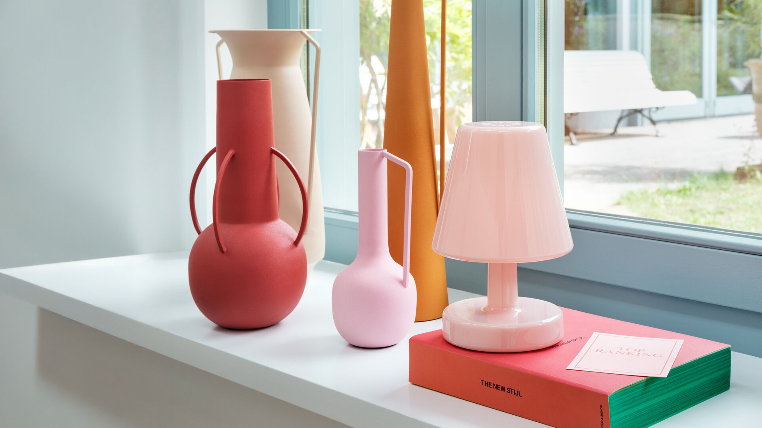 fatboy edison the ambience tischlampe in rosa neben vasen in pastellfarben auf einer fensterbank
