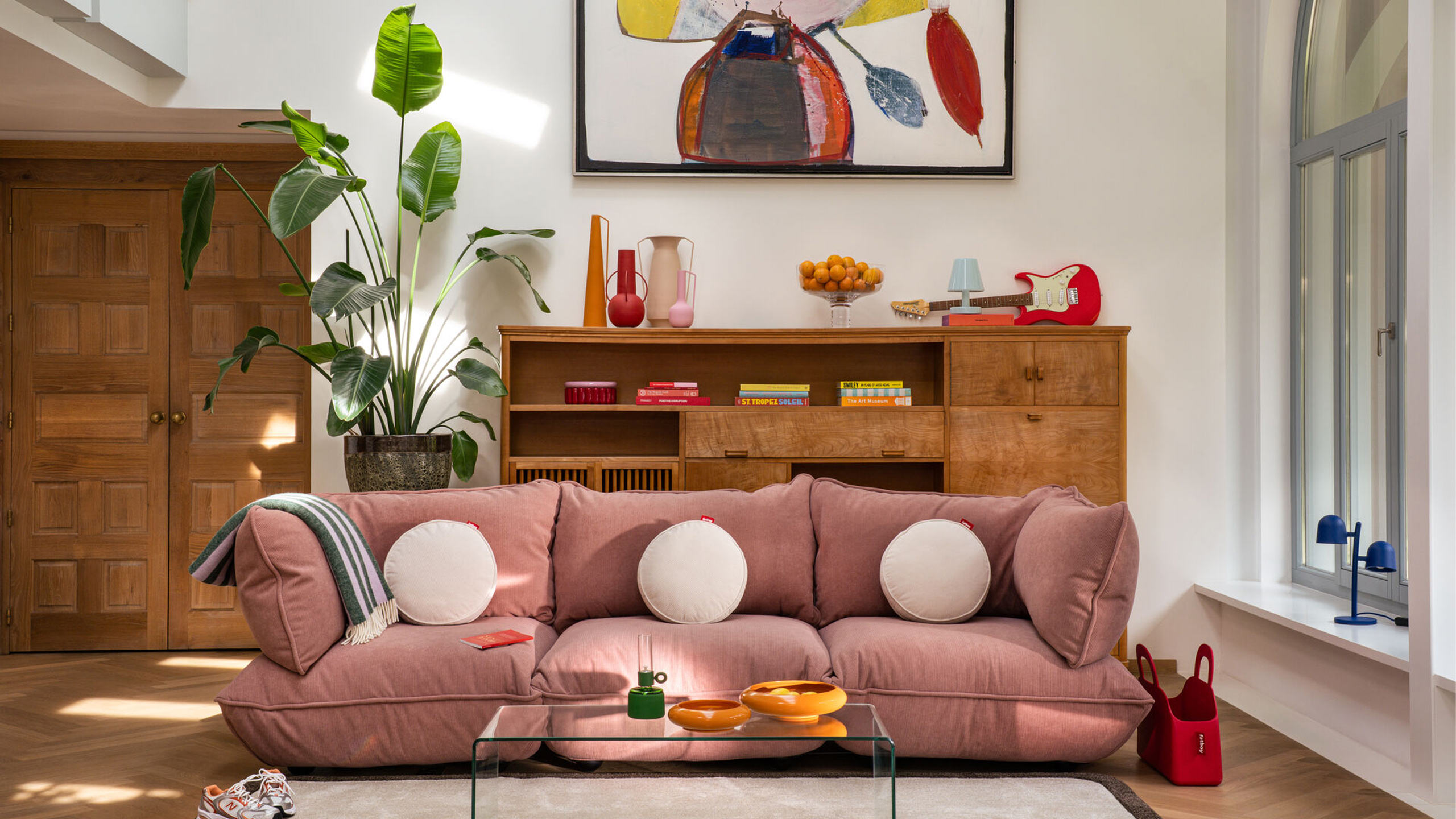 fatboy sumo cordsofa in rosa vor einem holz sideboard mit bunter deko
