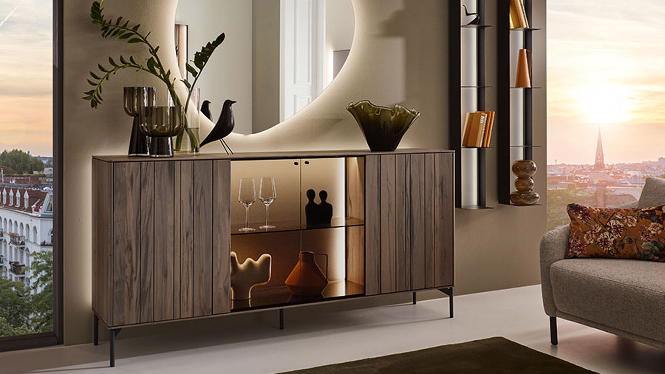 elegantes sideboard aus dunklem holz mit beleuchtung und glasvitrine aus der hartmann audra serie in einem loft wohnzimmer