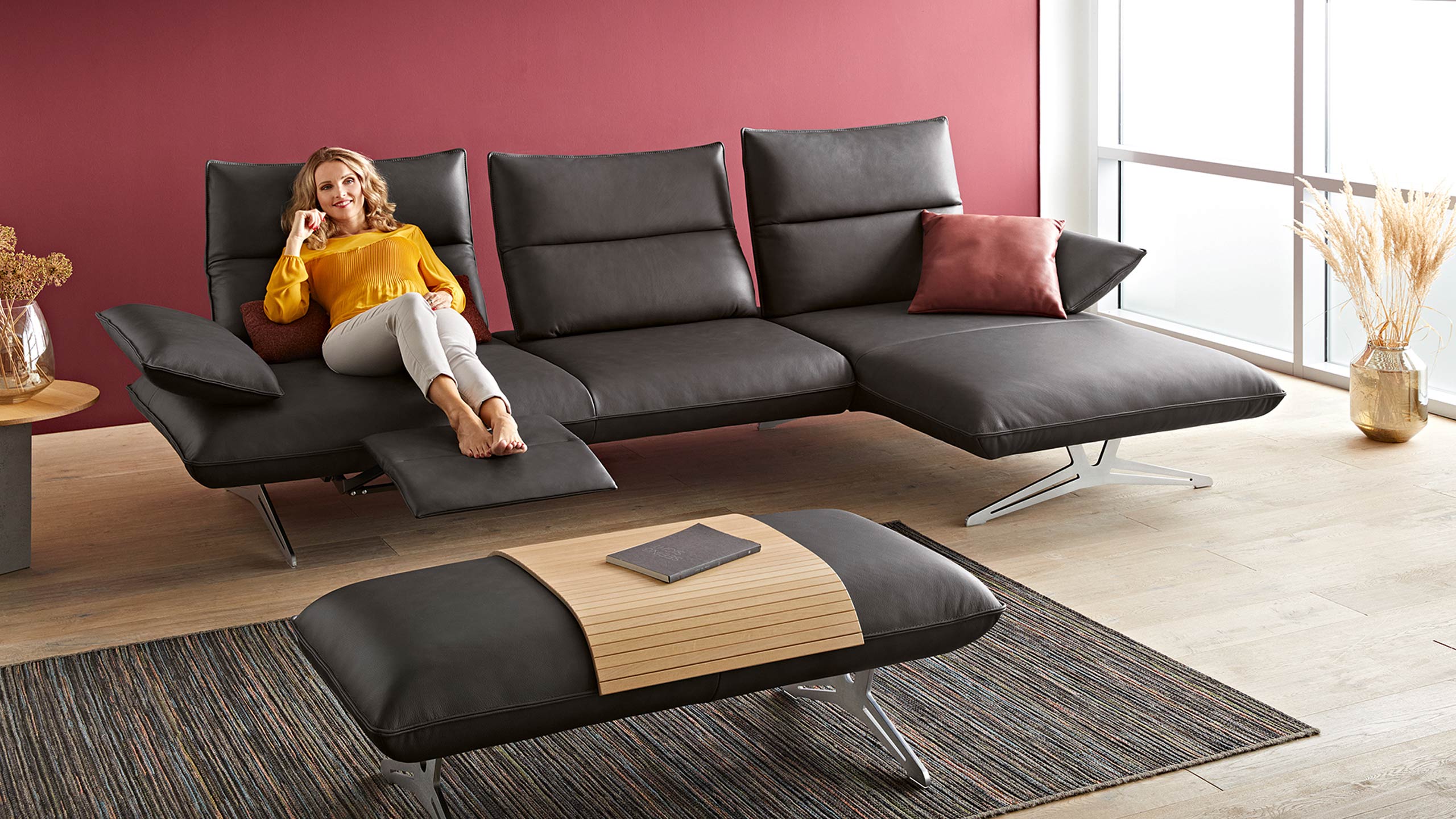 frau liegt auf einem schwarzen ledersofa aus der serie koinor caio
