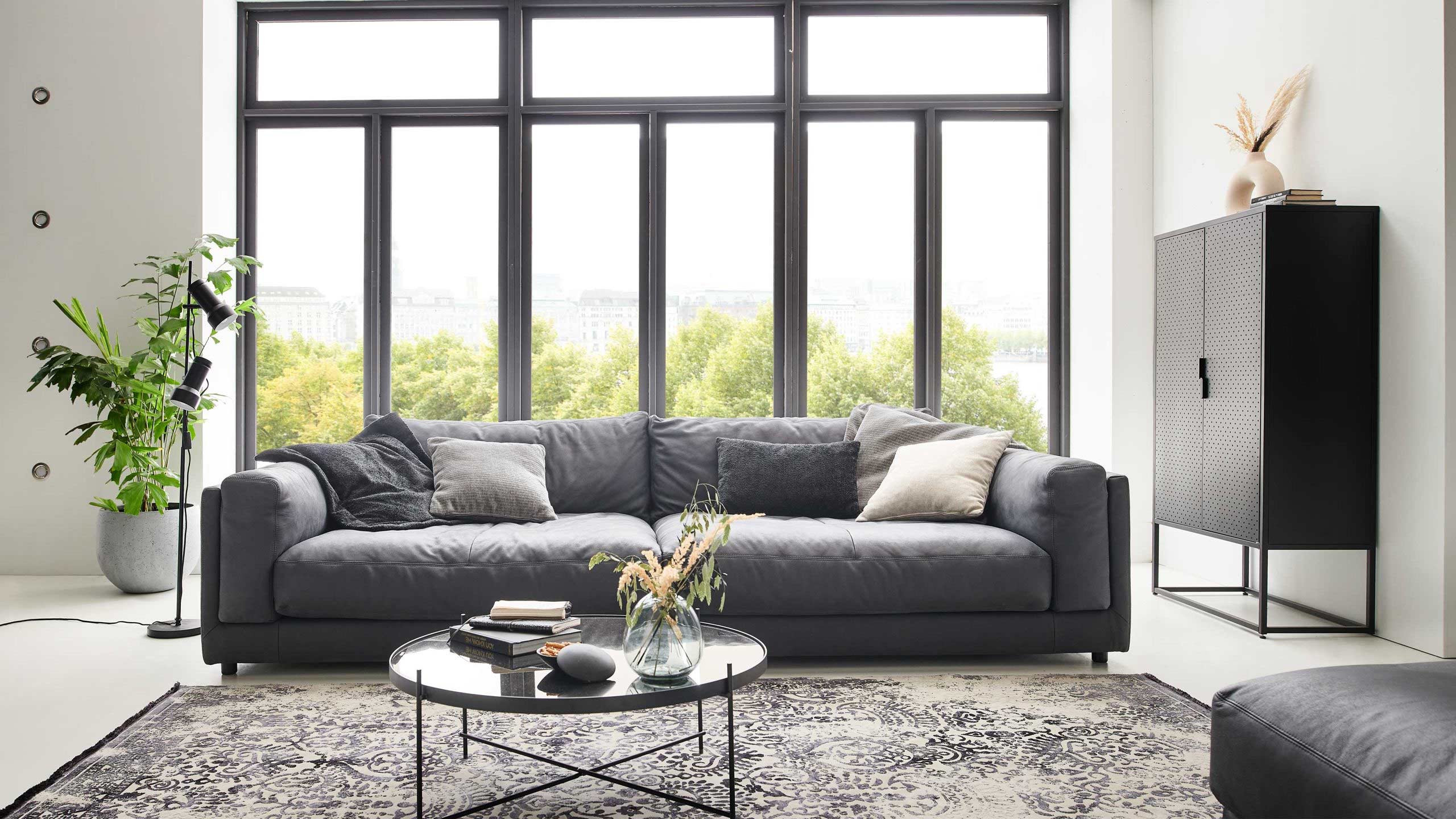 sofakultur sk 760 big sofa aus leder in schwarz vor einer großen fensterwand in einem schwarz weiß wohnzimmer