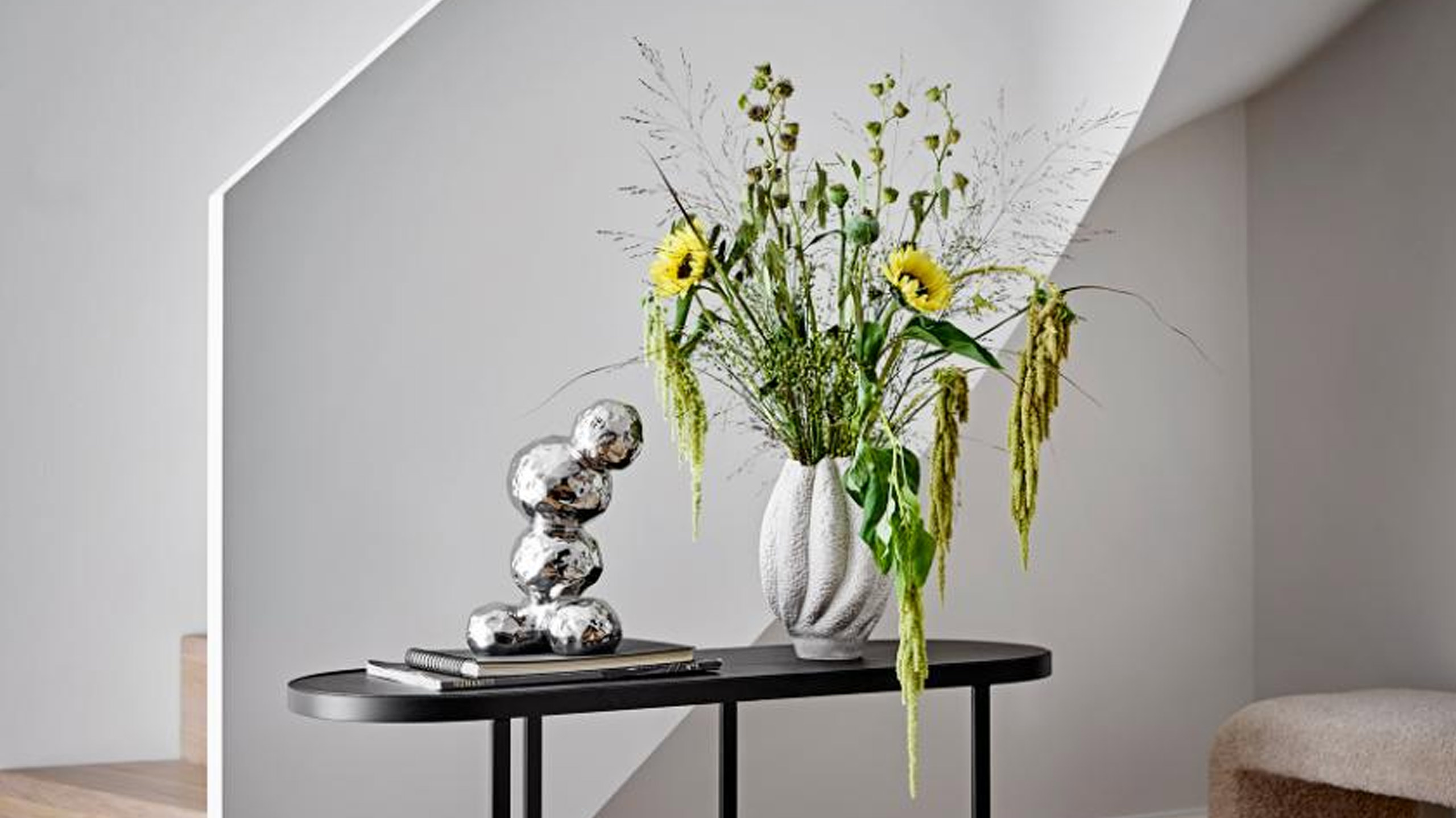 bloomingville bobby dekofigur aus chrom auf einem schwarzen beistelltisch neben einer vase mit sonnenblumen